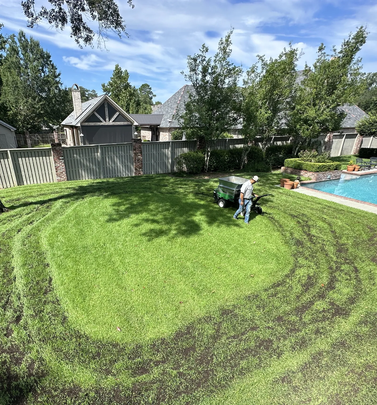 Treppendahl technician spreading compost topdressing across a backyard lawn with a topdresser in Baton Rouge, LA