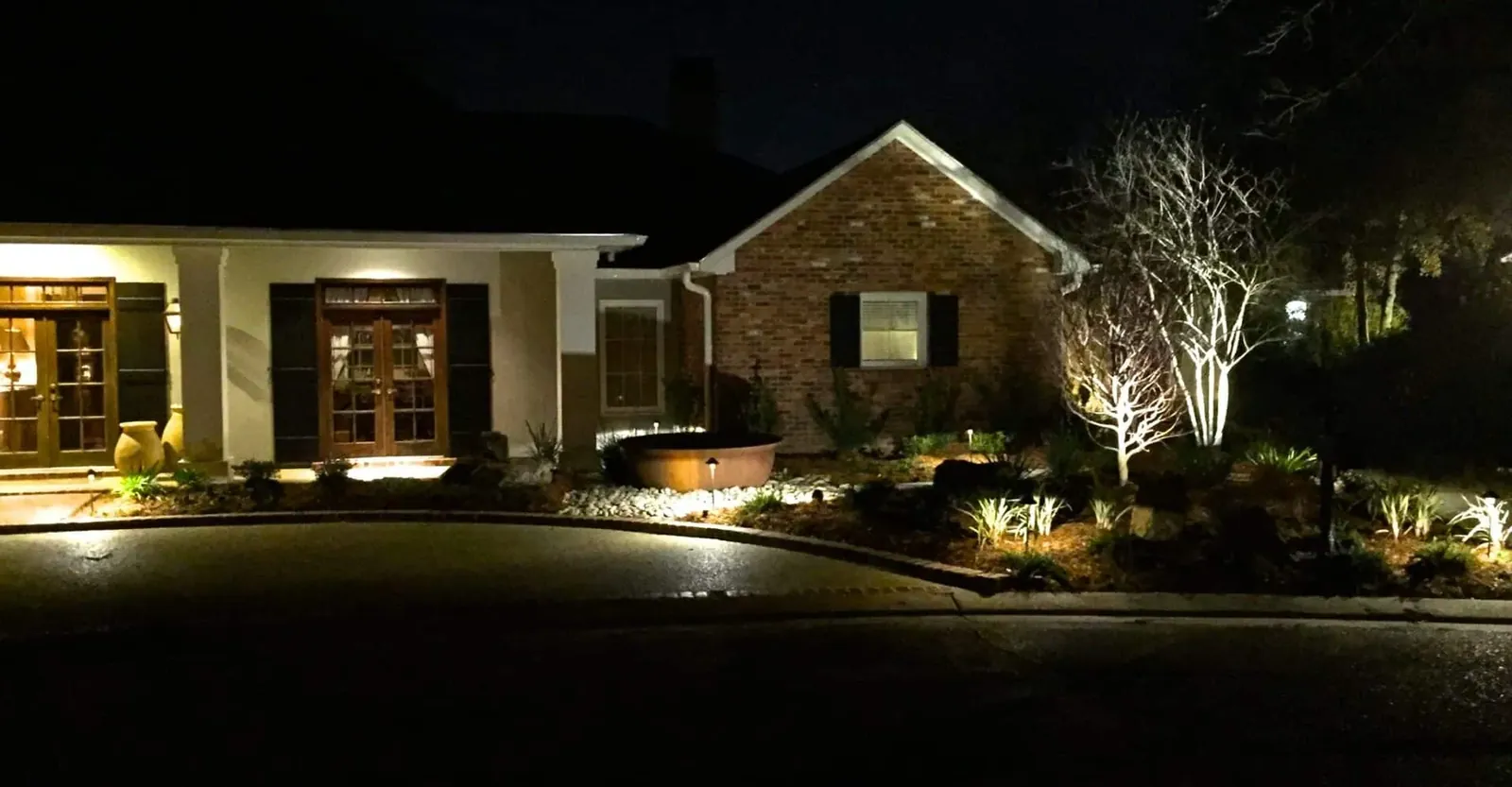 Landscape lighting on a home's facade and beds at night in Baton Rouge, LA