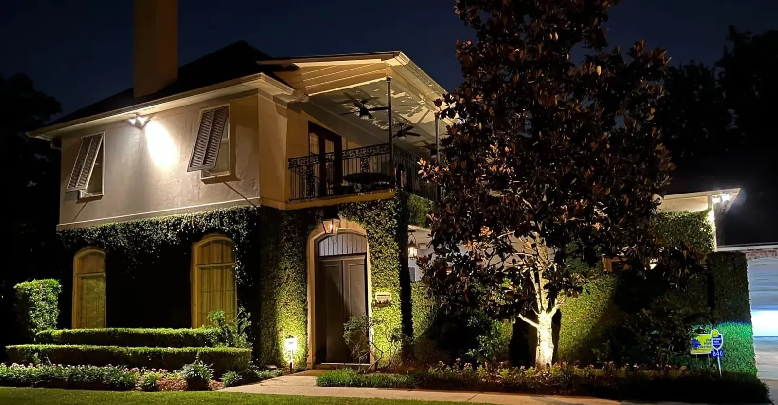 Two-storey home and magnolia uplit with landscape lighting at night in Baton Rouge, LA